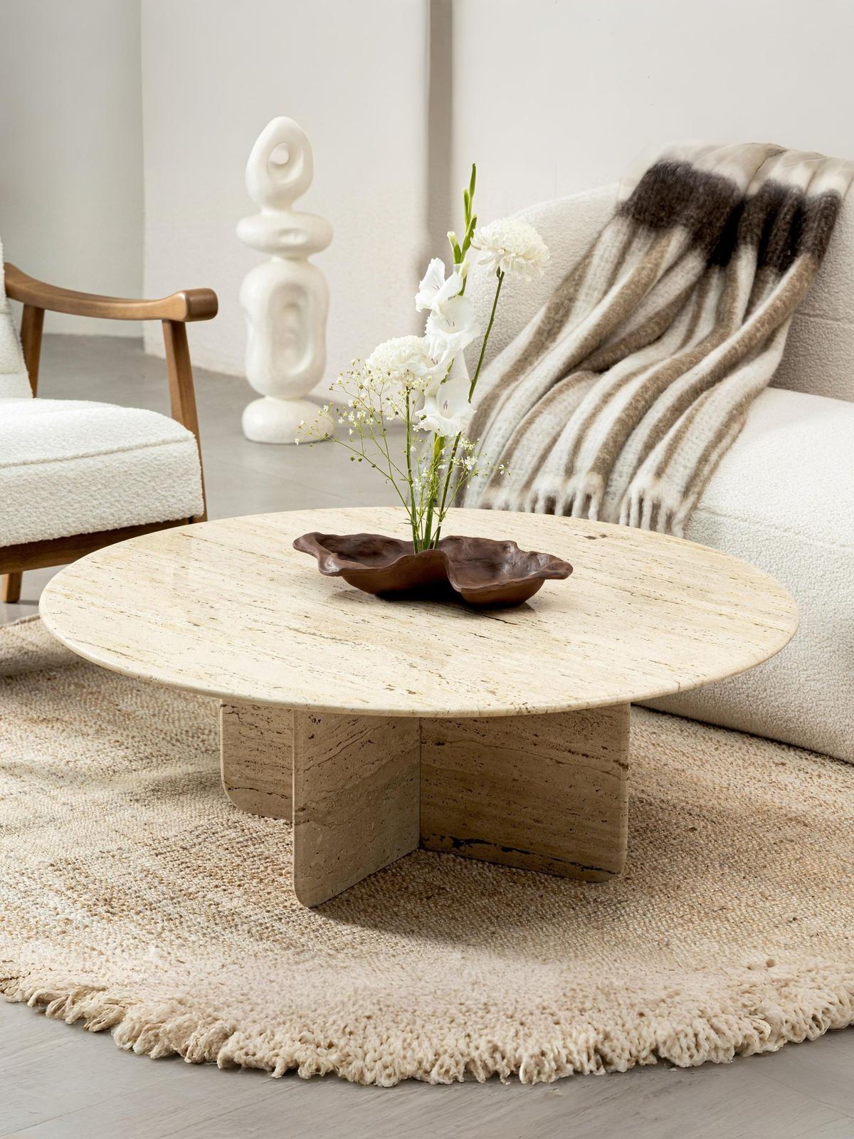 Round travertine coffee table with wooden bowl in modern living room
