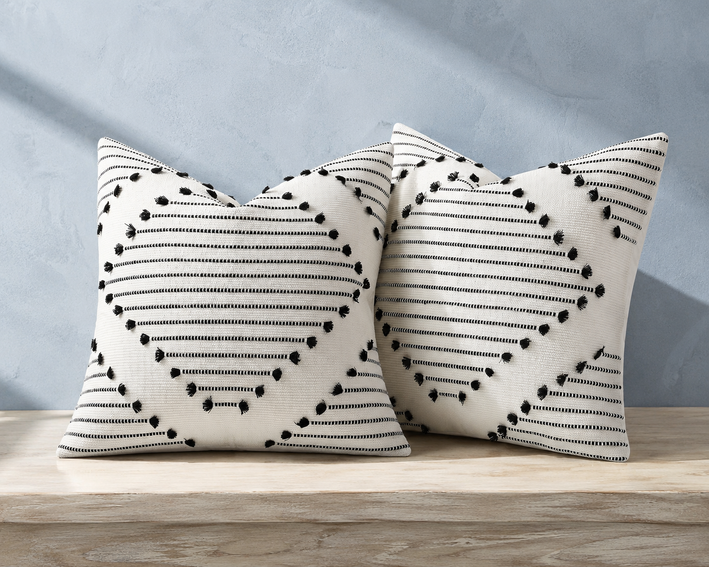 Two black and cream Mecatny woven pillow covers with stepped stripe and tuft details
