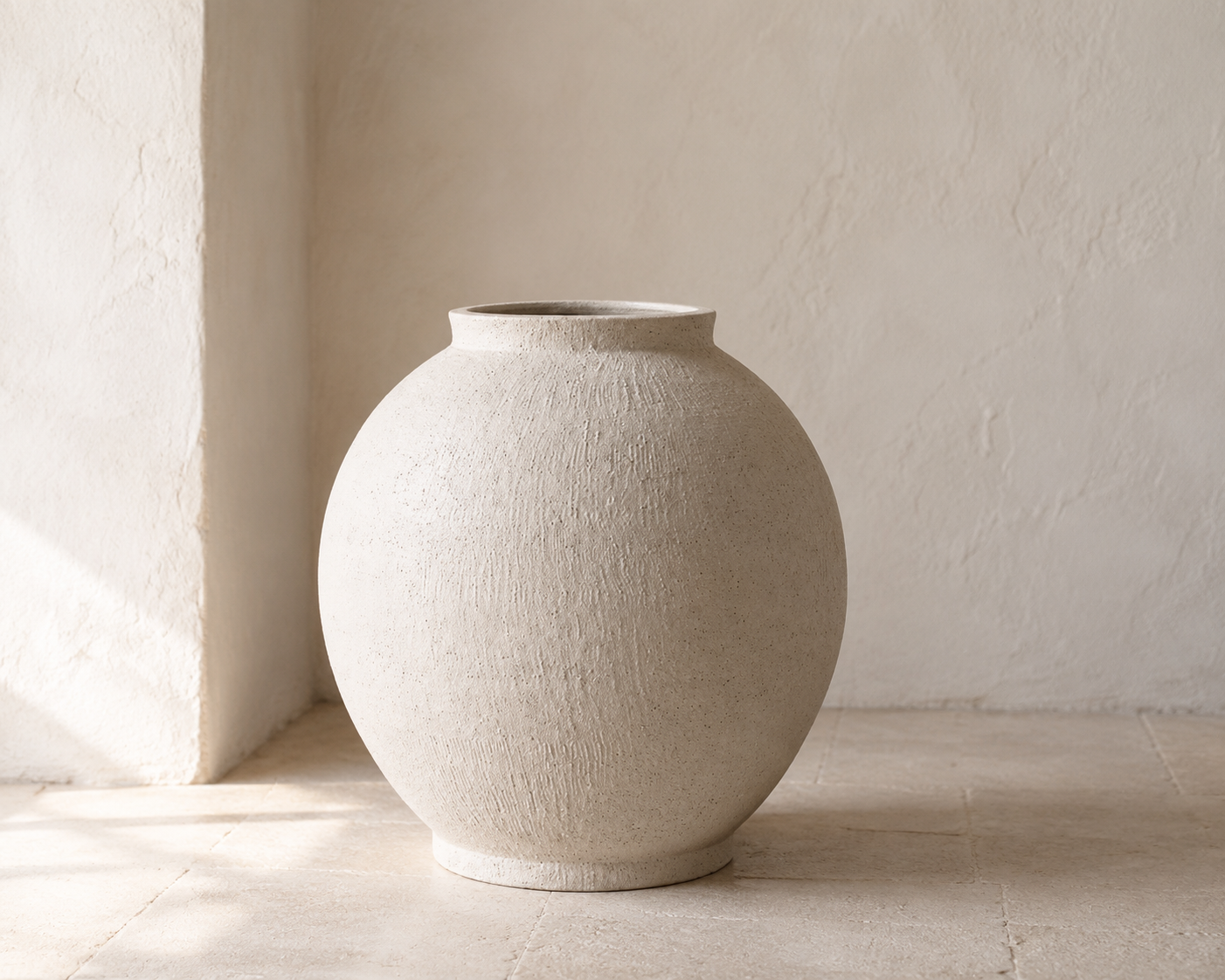 Warm sandstone-white LE TAUCI GARDEN Kora ceramic vase in a sunlit stucco alcove